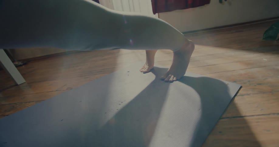 Legs of a woman without shoes stretched out on a fitness mat in a stretching position
