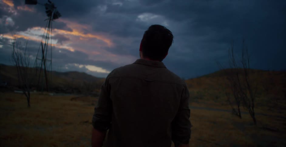 A man takes off his straw hat as he looks into the distance