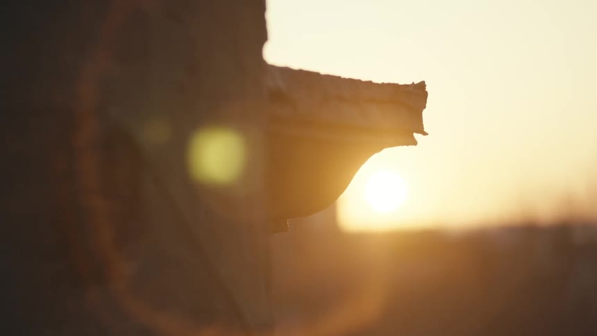 The side of a building and its ledge, with the sunset in the background