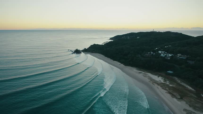 An aerial view of a beach with rolling waves crashing on shore
