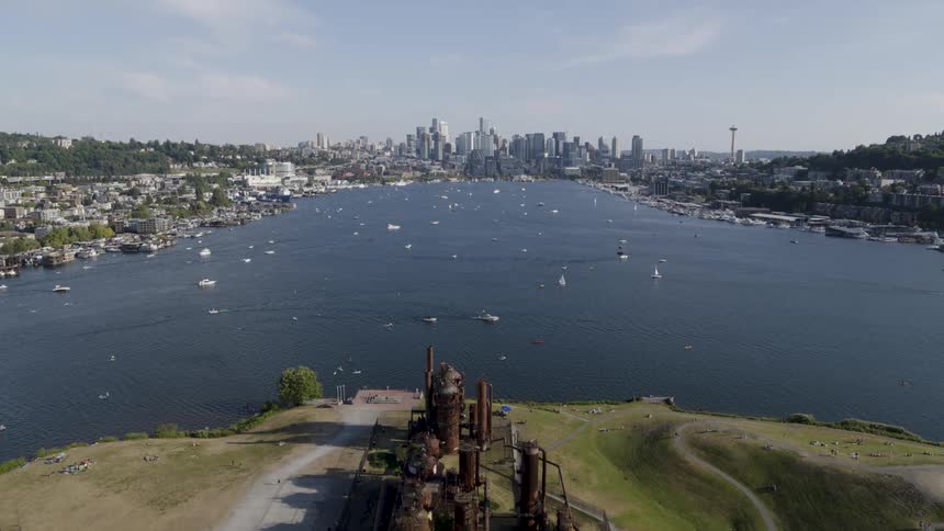 Low traverse over Gasworks Park towards people on kayaks and paddleboards enjoying Lake Union on a summer afternoon