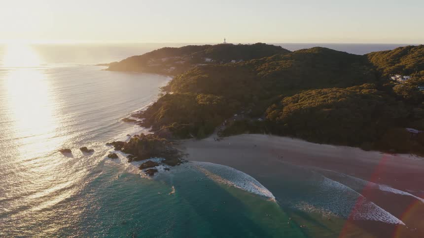 Aerial of people surfing ocean waves in a small seaside community