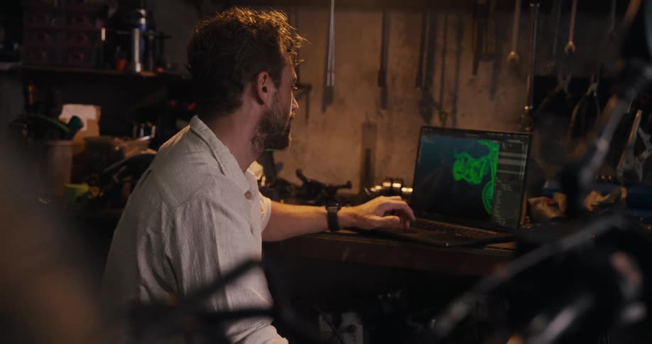 Man inside a mechanic workshop working on a laptop on a project