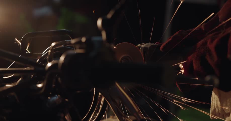 Gloved hand using a saw on metal and sparks coming out