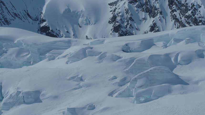 A vast snowcovered mountain landscape with rugged peaks and glaciers stretching towards the horizon