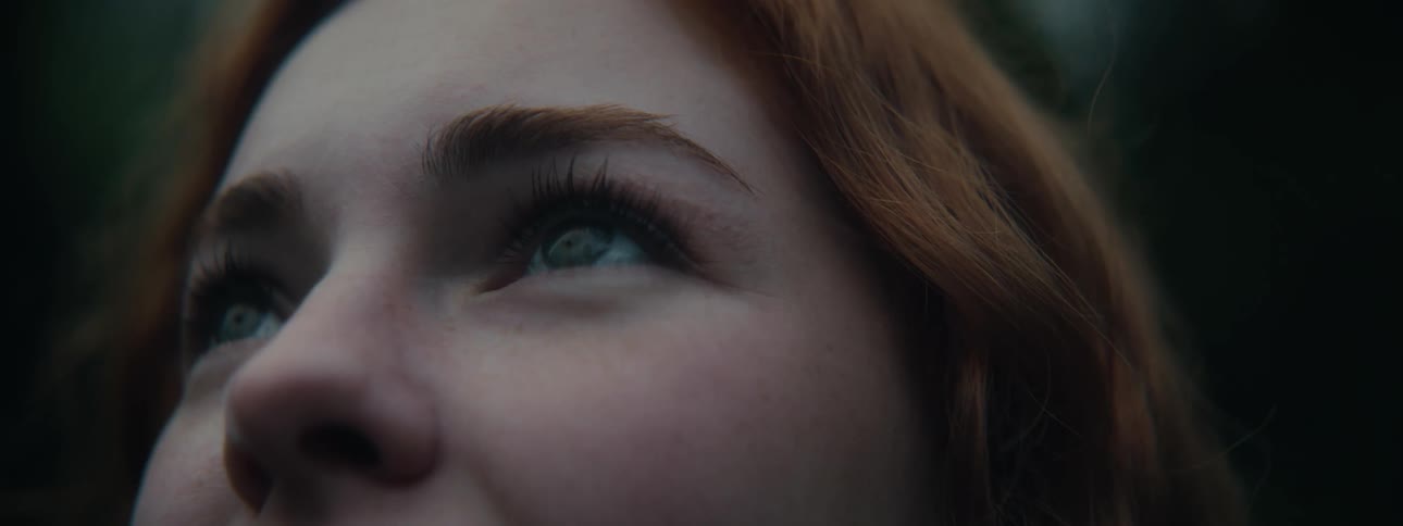Portrait of a young redheaded woman in an outdoor setting looking up