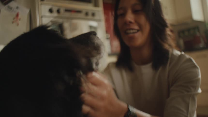 Person in kitchen petting a dogs neck