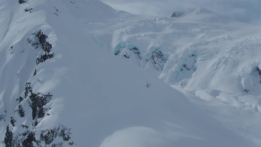 A vast expanse of snow covered mountains with a glacier visible in the distance
