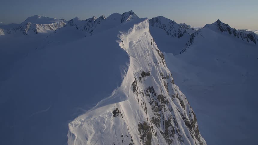 A snowcovered mountain ridge stretches out into the distance with a steep dropoff on one side