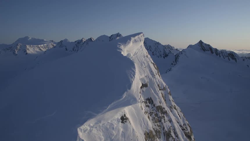 Aerial panorama of mountains with snowcapped cliffs on a clear sky morning