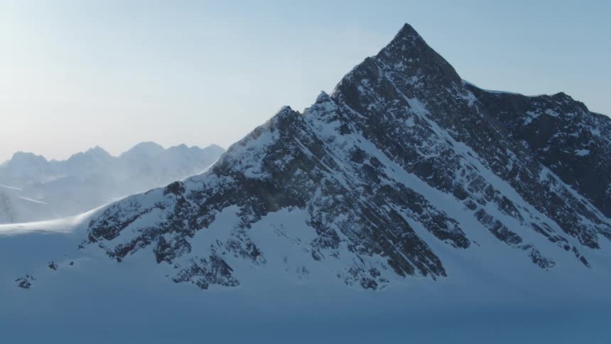 The mountains are covered in snow on a sunny day