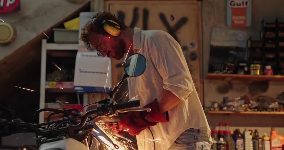 Mechanic using a sparkproducing tool on a motorcycle in a workshop garage