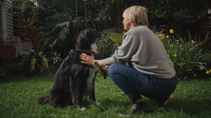 Woman crouching in the garden petting a dog