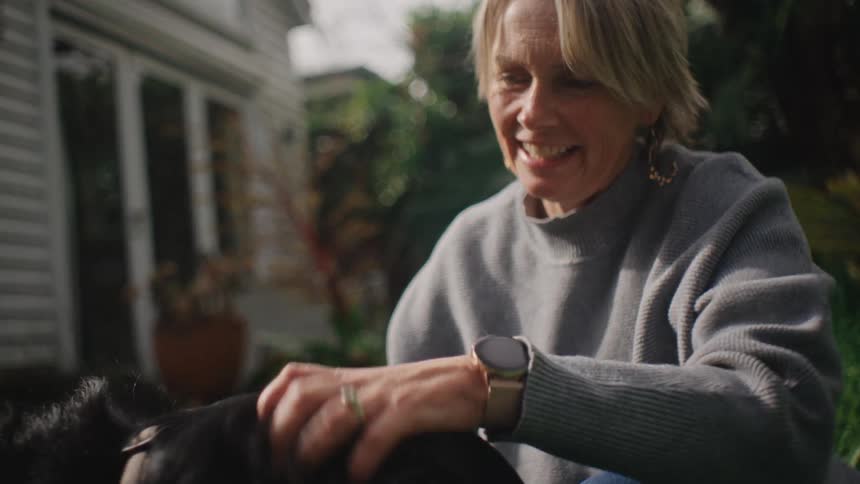 Woman in a backyard petting a dog