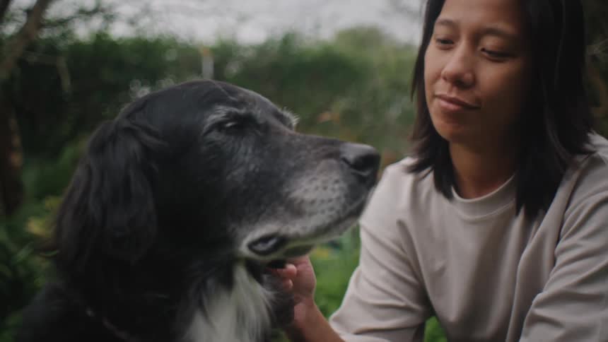 Woman in a garden next to a dog with black fur