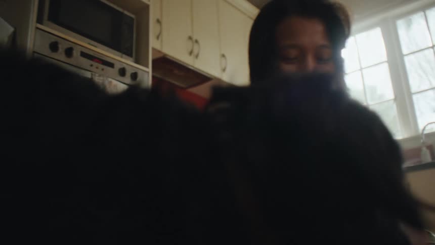 A woman is feeding her dog in the kitchen