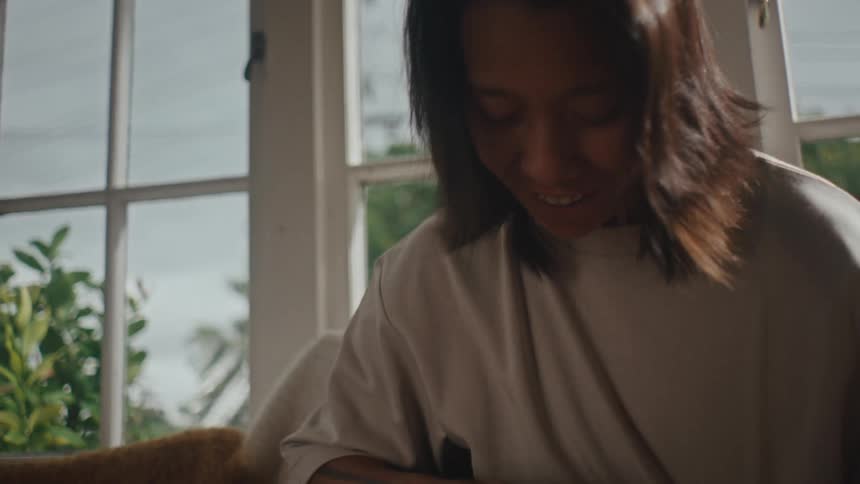 A woman strokes a black and white dog on the living room couch