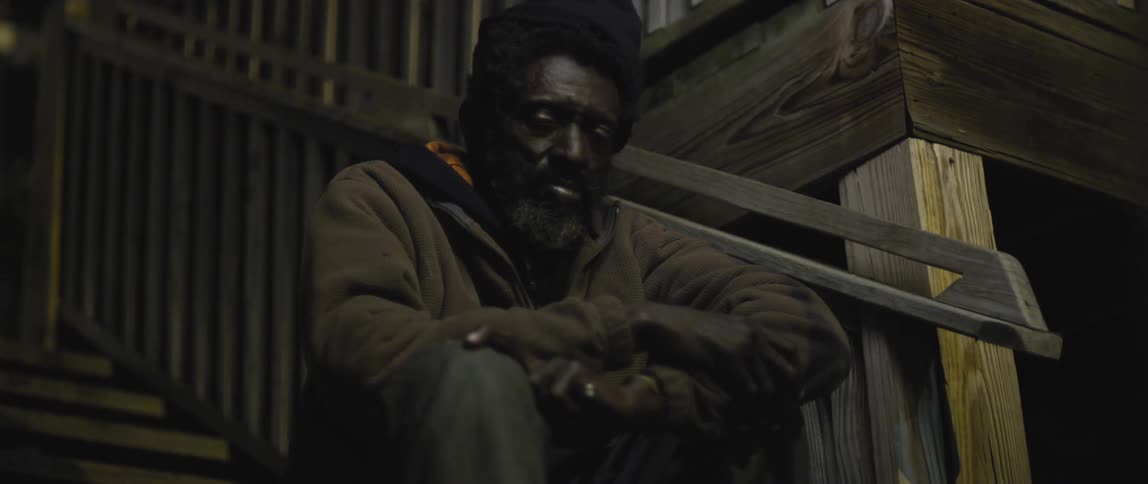 A man sits with his arms folded on steps