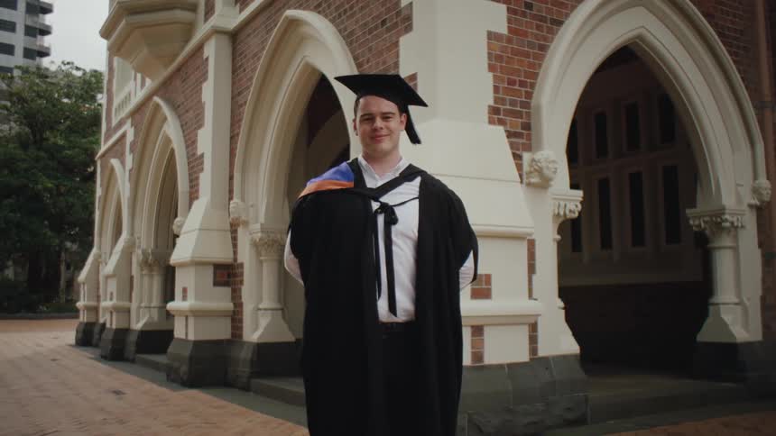 Man in graduation robes in an outdoor setting