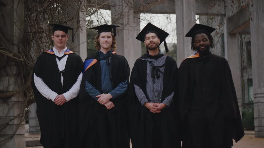 Four men posing in graduation gowns