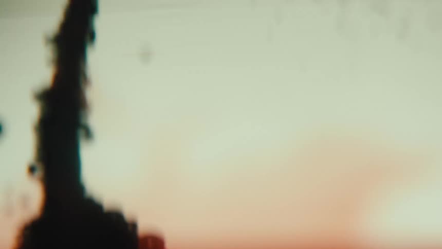 Outoffocus footage of dark red ink streaming irregularly in liquid