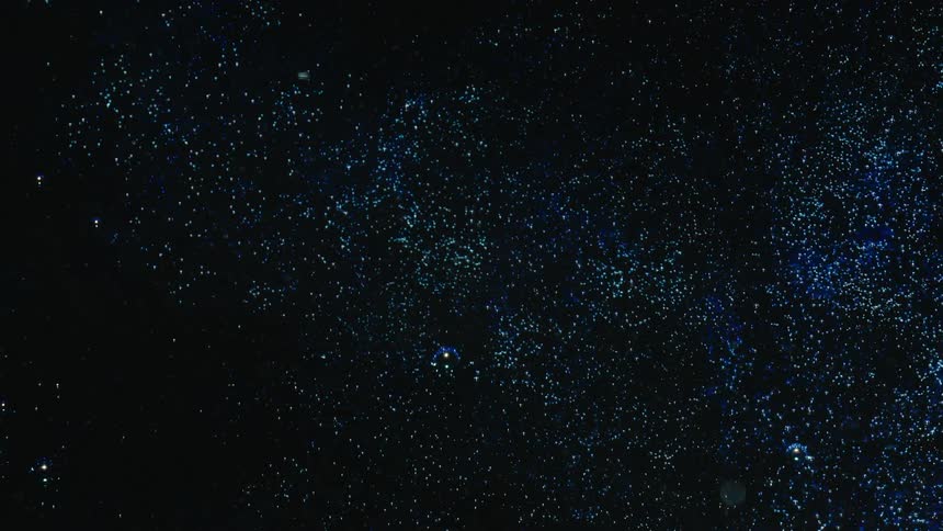 Dark blue liquid is sprinkled with small blue sparkly dots