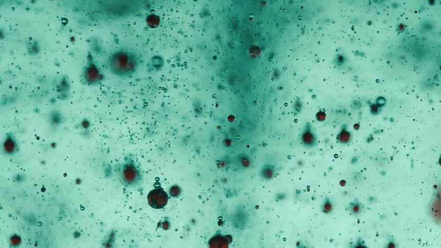 Extreme closeup of bubbles moving through a green liquid substance