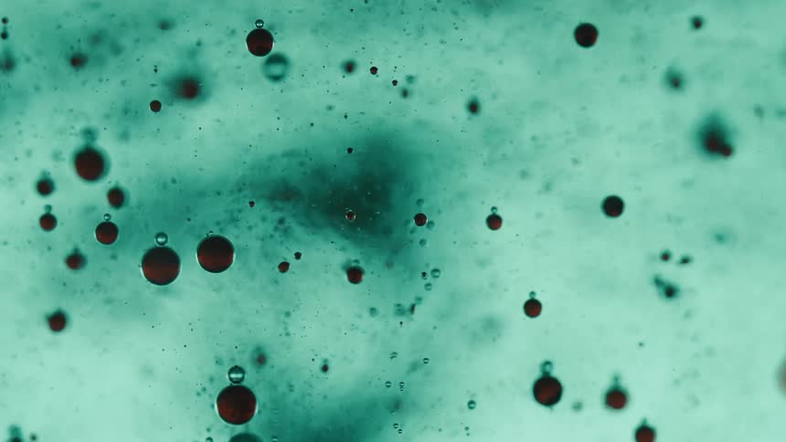 Close up of red ink and air bubbles floating on a blue liquid