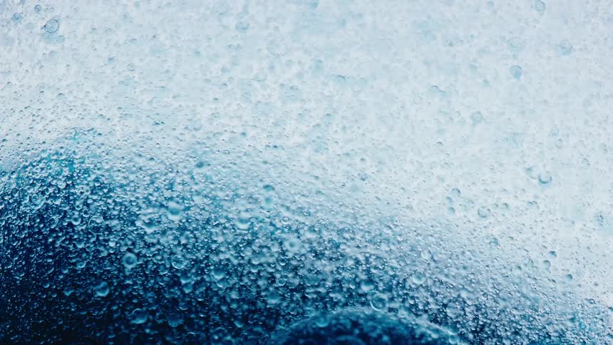 Close up of small air bubbles trapped inside a thick blue liquid