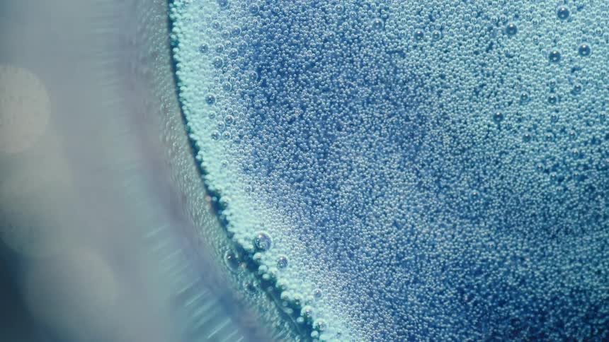 Blue colored liquid with small abstract dots and circular movements