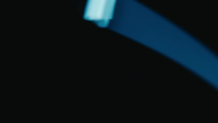 Blue neon light in rotating motion against a dark background