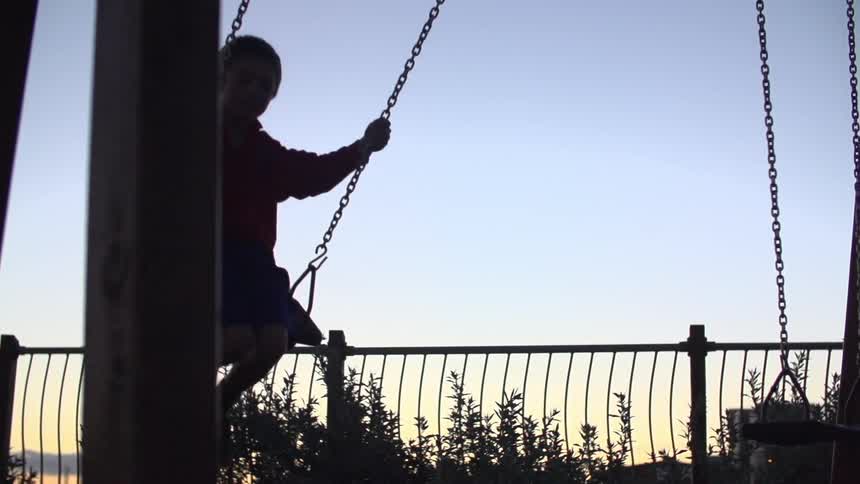 A child swings on a swing set at dusk