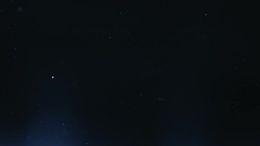 Tiny glowing particles float in a dark expanse