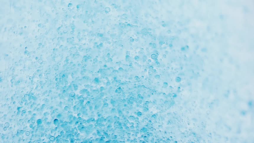 A swirling mass of effervescent bubbles dances and twirls in a pool of vibrant blue creating a mesmerizing spectacle