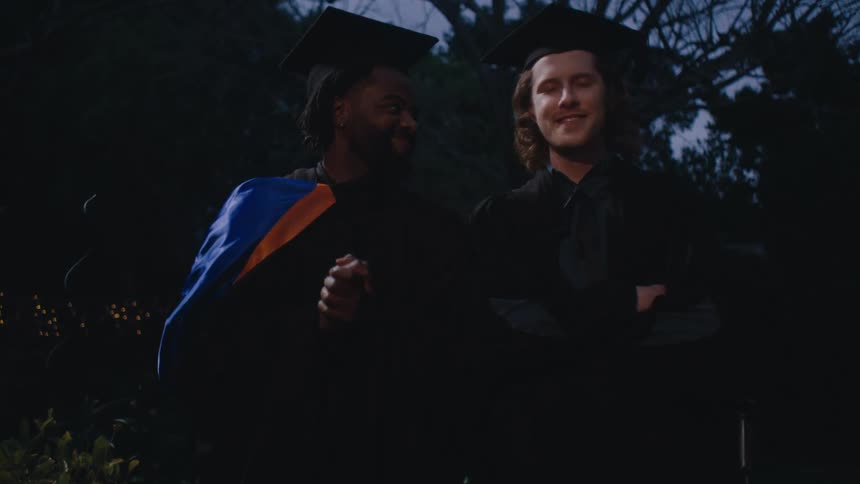 A medium clip of two happy graduating students posing for a picture