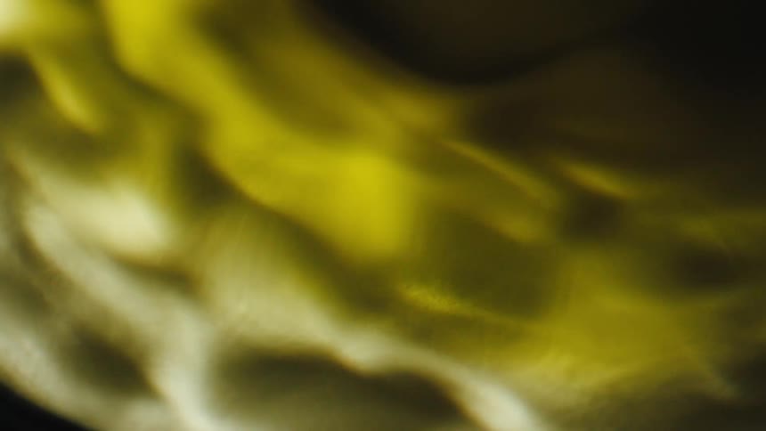 A close up of a swirling mass of yellow and white spinning under a clear liquid