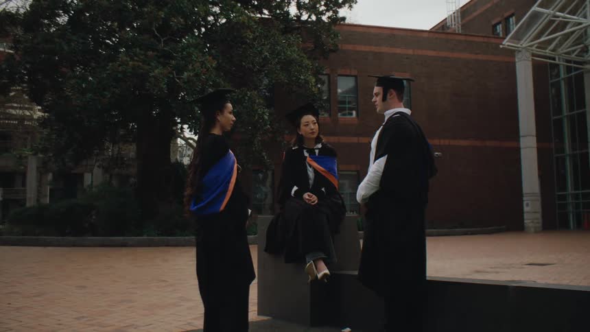Man and two women with decades of graduation talking
