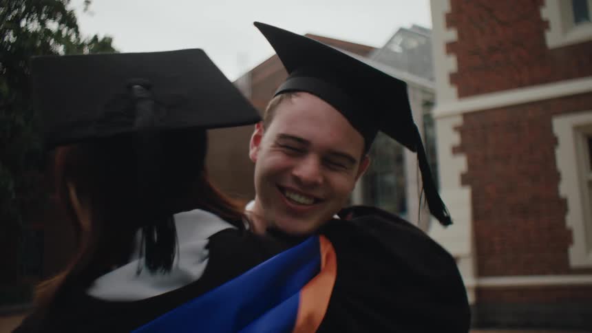 Graduating seniors smile while hugging each other outside a campus building