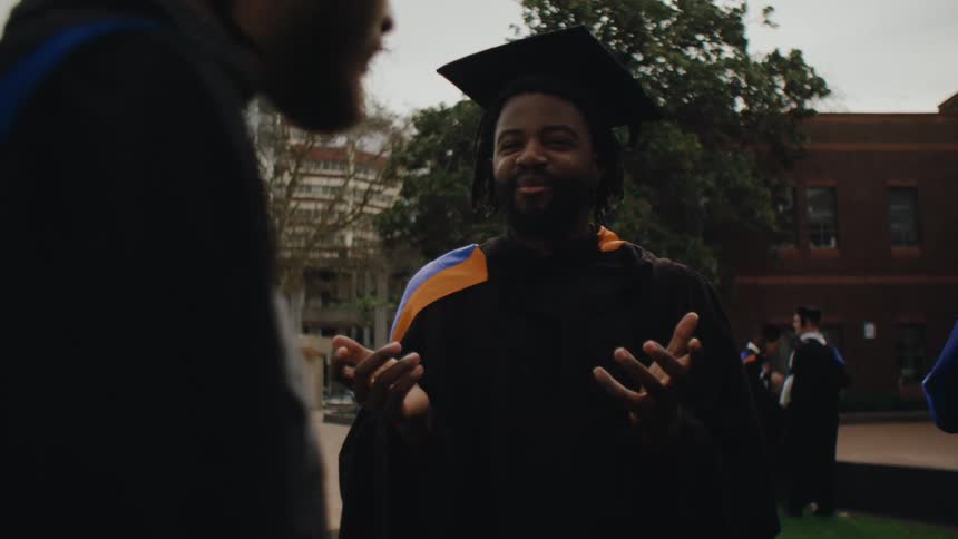 Students in graduation gowns talking to each other