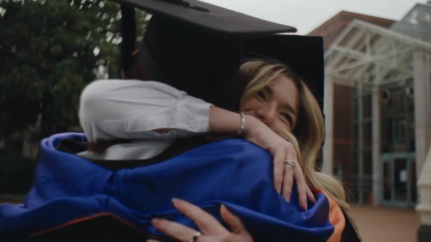 Two women hugging each other while both wearing graduation attire