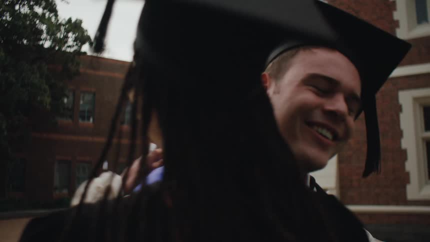 Man smiles before hugging his female fellow graduate