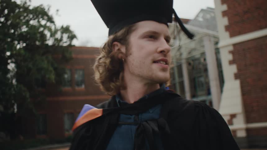 College students in graduation gowns greeting each other with hugs