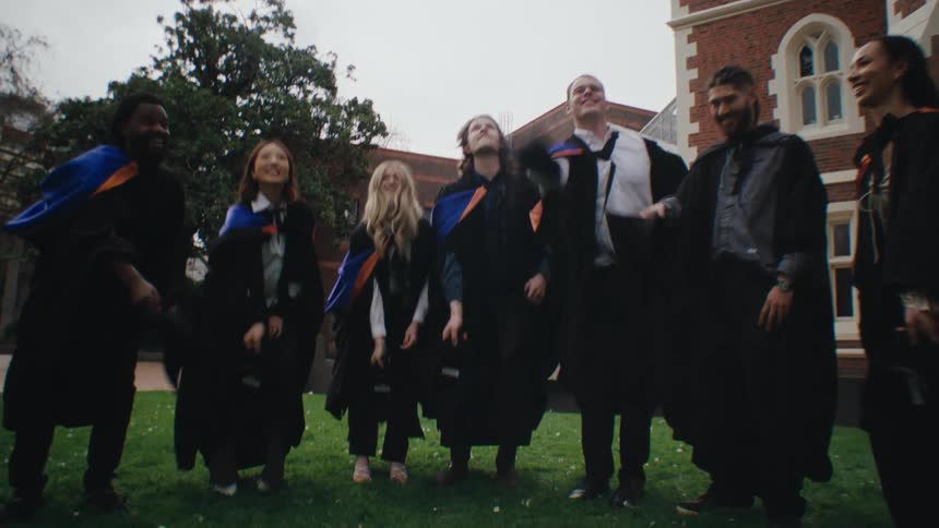 Group of friends graduating in graduation attire throwing their hats in the air