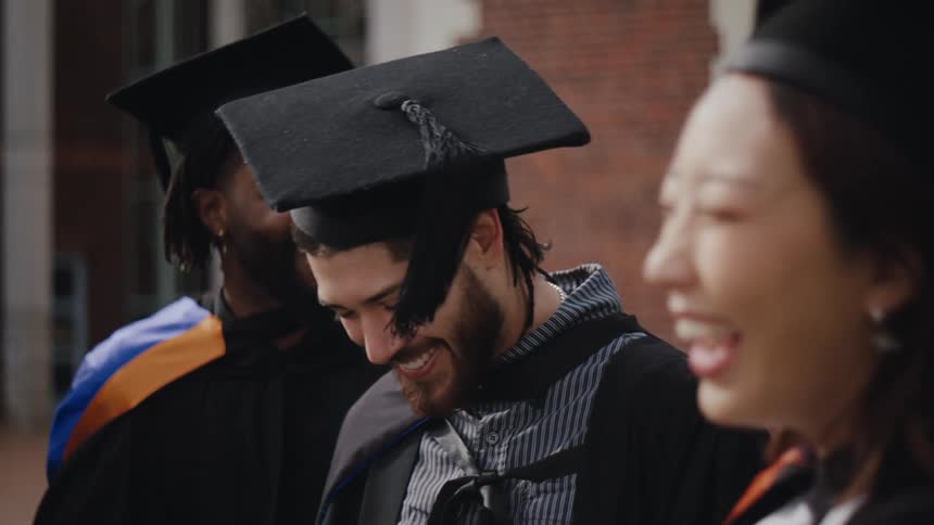 A group of happy graduate students wearing black academic cap and gown