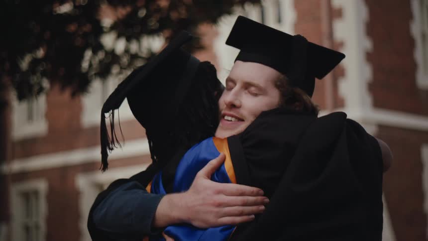 A clip of male graduates sharing a hug