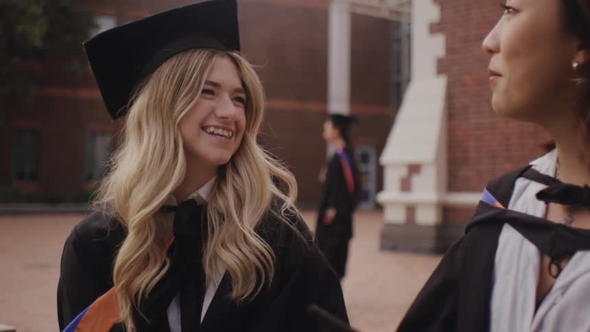 Friends and fellow graduates talk in their graduation regalia