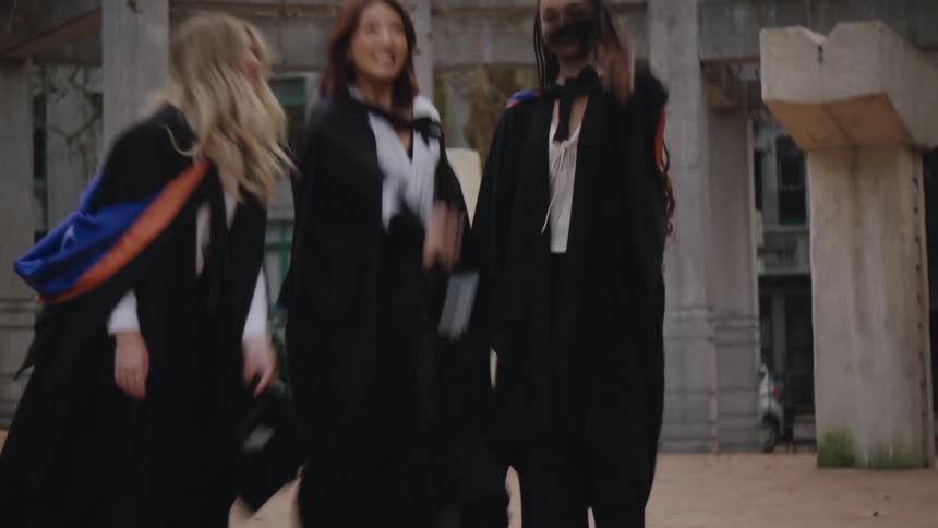 A clip of three female graduates throwing their hat in the air