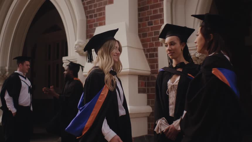 Graduate friends with gowns talking to each other