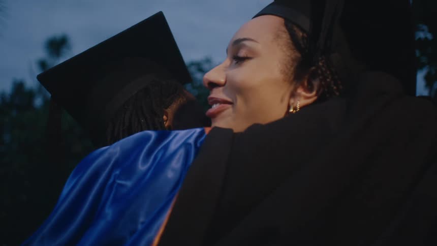 A professor hugs a student at a graduation ceremony