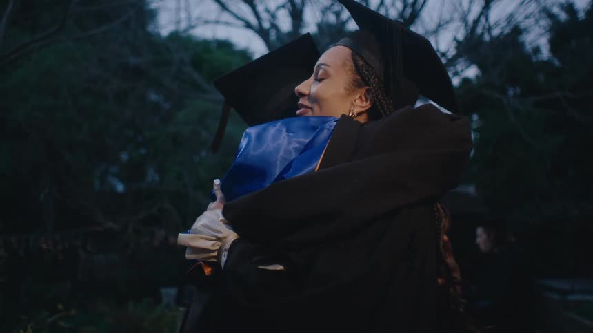 College graduates hugging in accomplishment outdoors